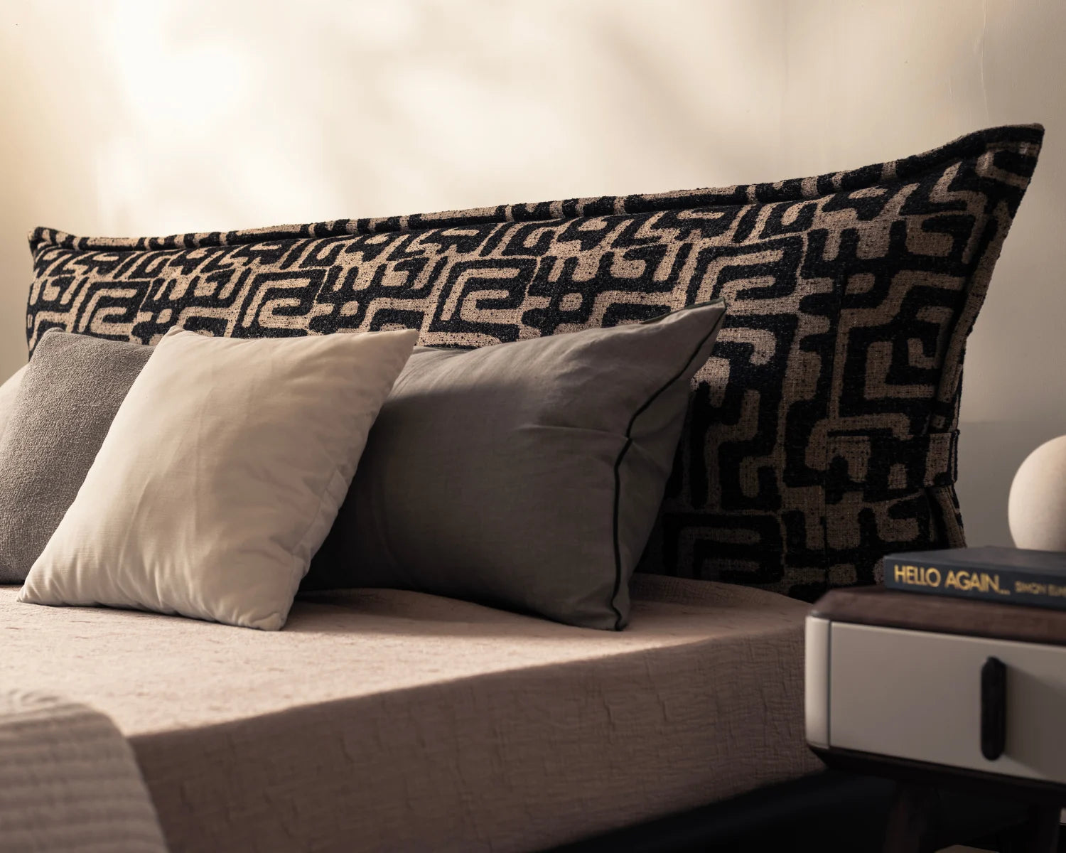Patterned pillow on a sofa with neutral-toned pillows and a book in the background.